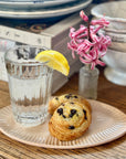 Glass of water with lemon slice on Heirloom Vanity Tray next to two pastries and books on wooden table.
