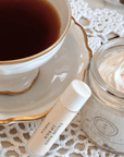 Amelia Vanilla Whipped Tallow Balm by Clara & Fritz in a jar, next to a teacup on a lace tablecloth.