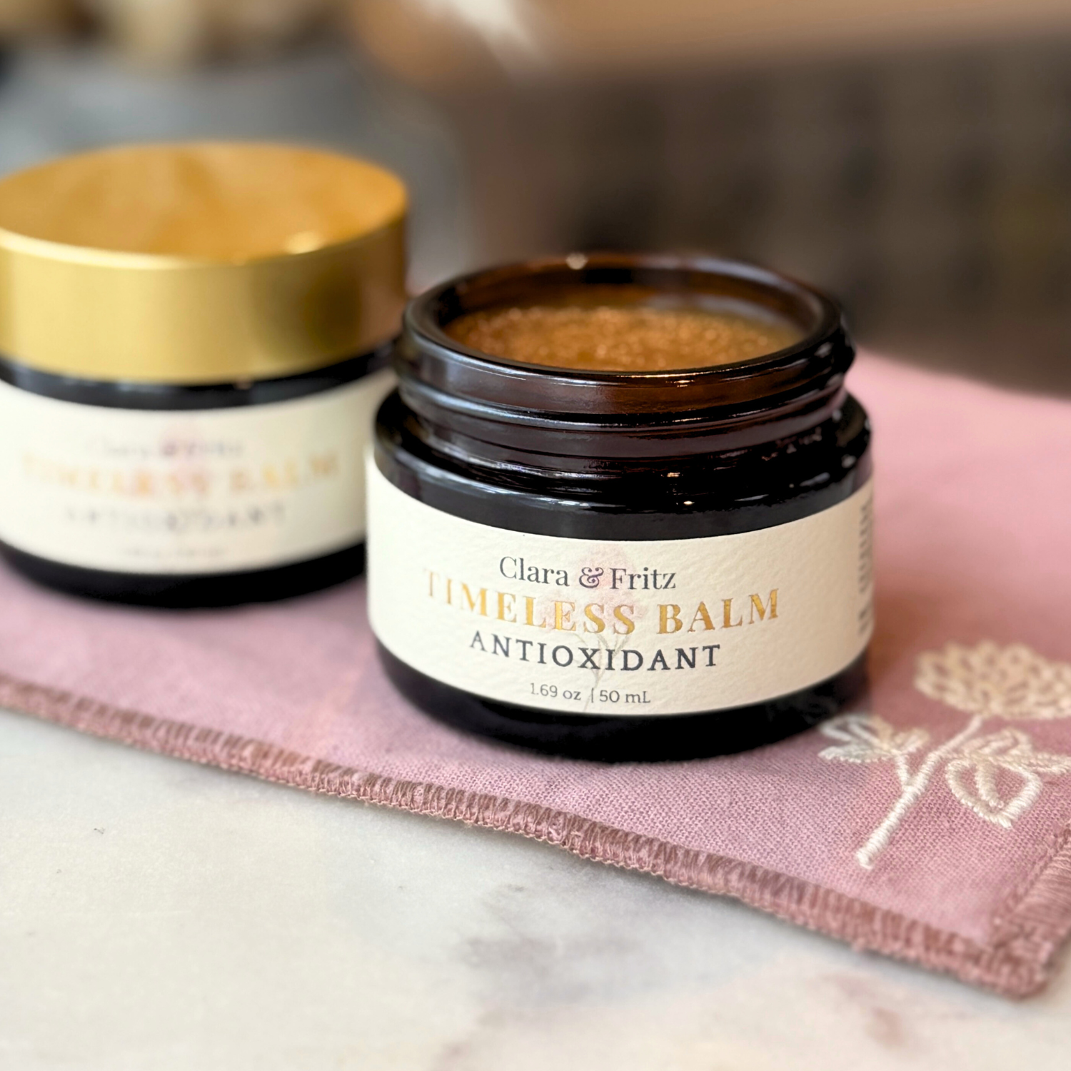 Timeless antioxidant balm jar on a pink towel, promoting radiant and resilient skin.