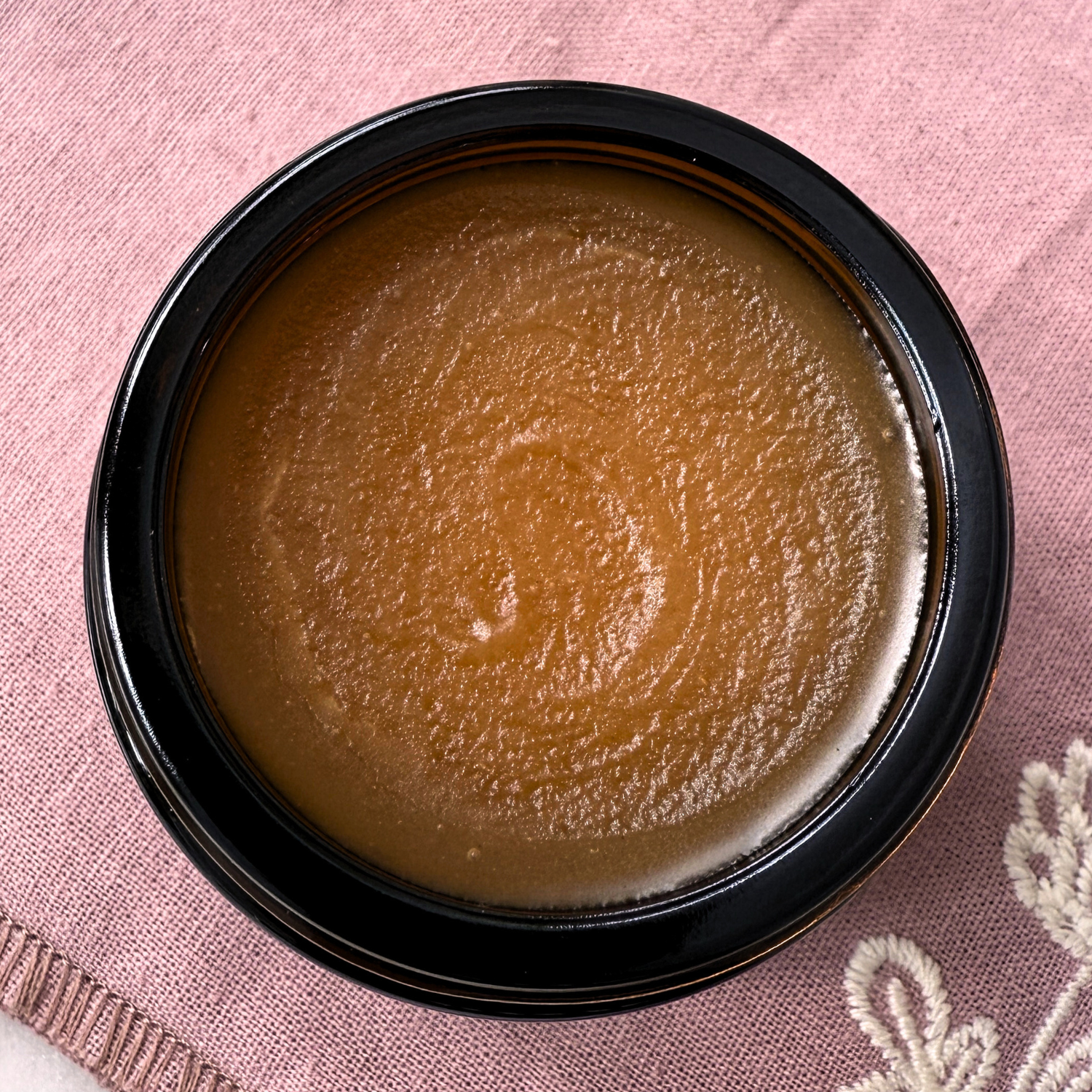 Timeless antioxidant balm in a jar on pink fabric, rich facial moisturizer for radiant skin.