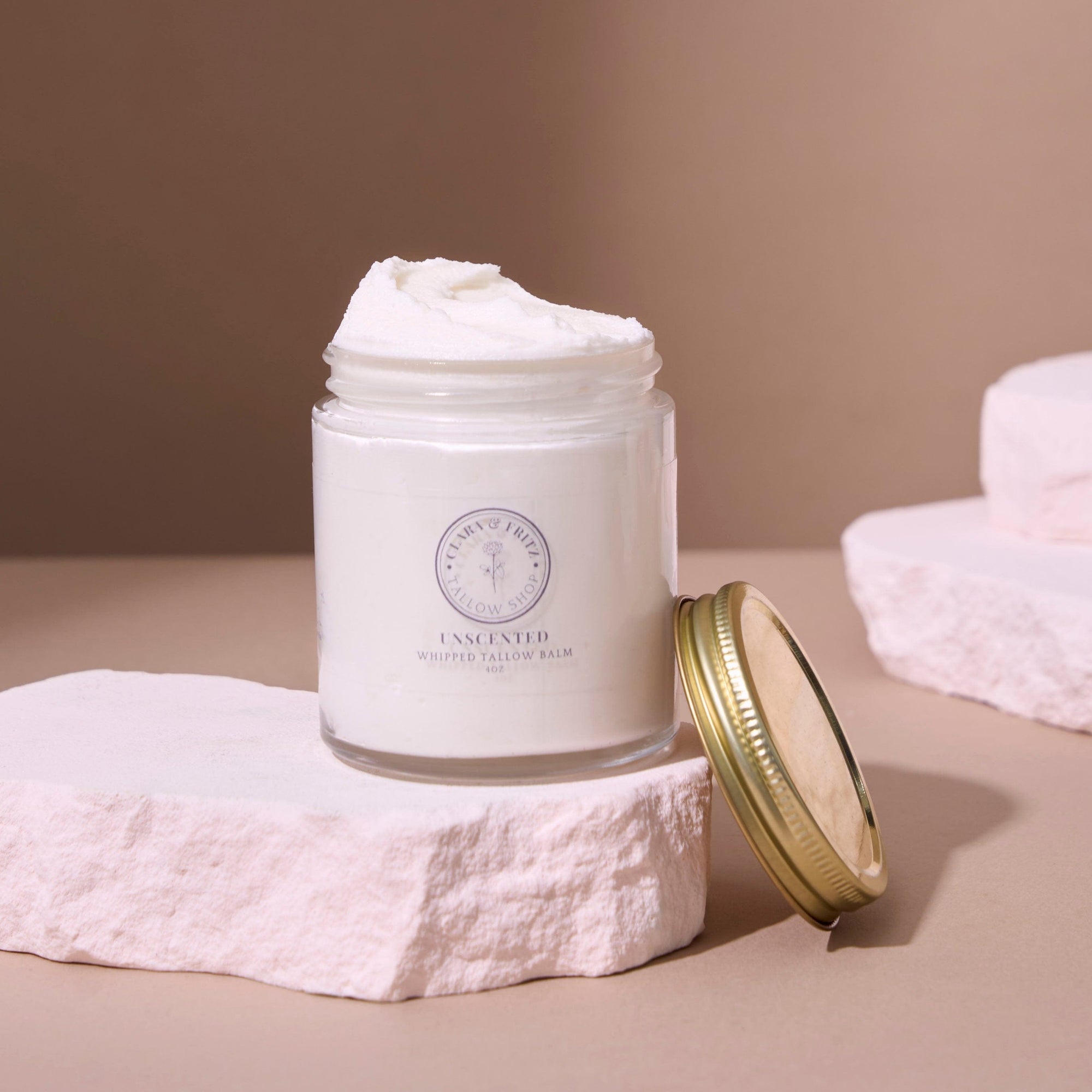 Open jar of Whipped Pure Hydration Set unscented whipped tallow balm on a textured surface, highlighting its creamy texture.