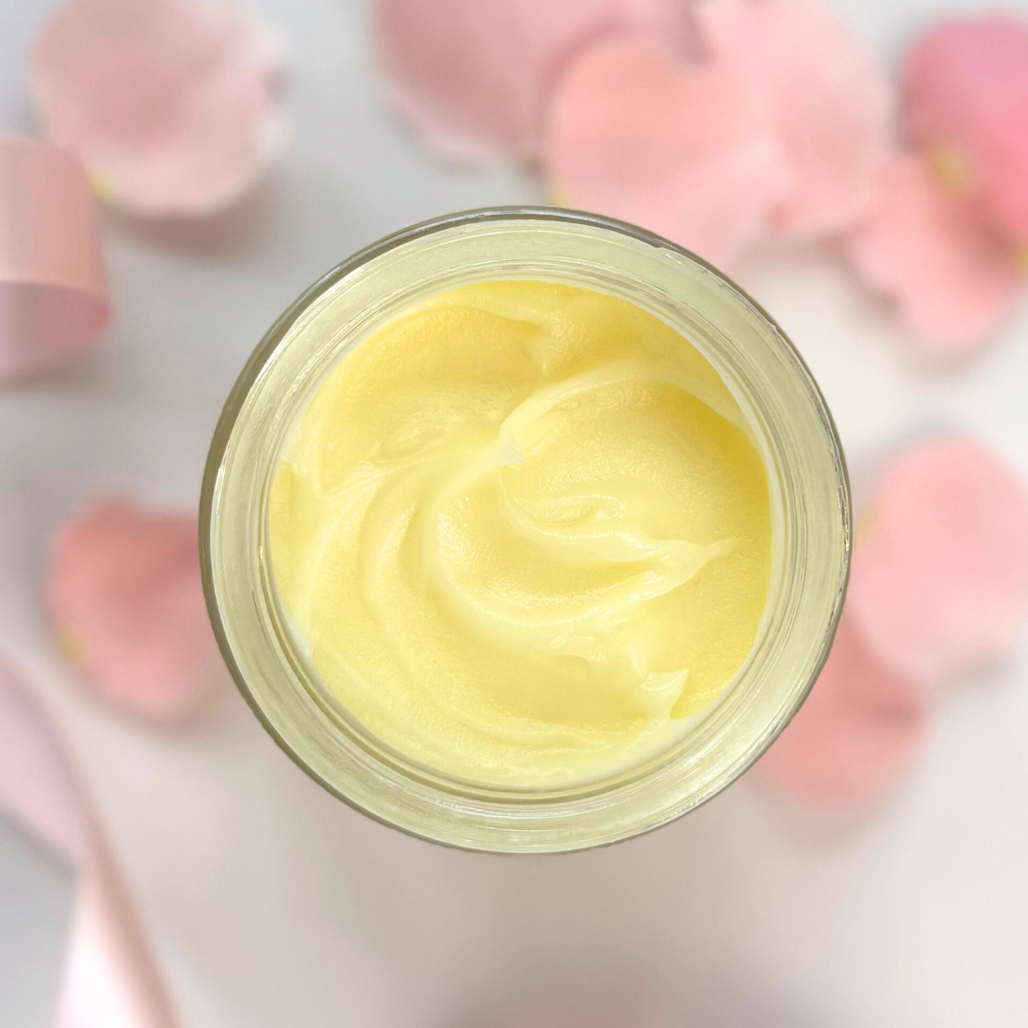 Open jar of Counterpane Tallow Night Cream surrounded by pink petals.