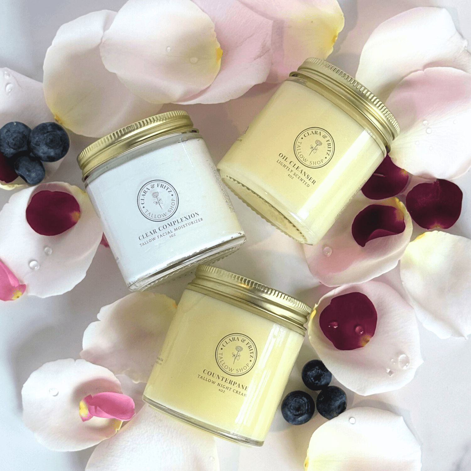 Daily Facial Trio from Clara & Fritz - Tallow based skincare products surrounded by rose petals and berries. Full-size skincare jars
