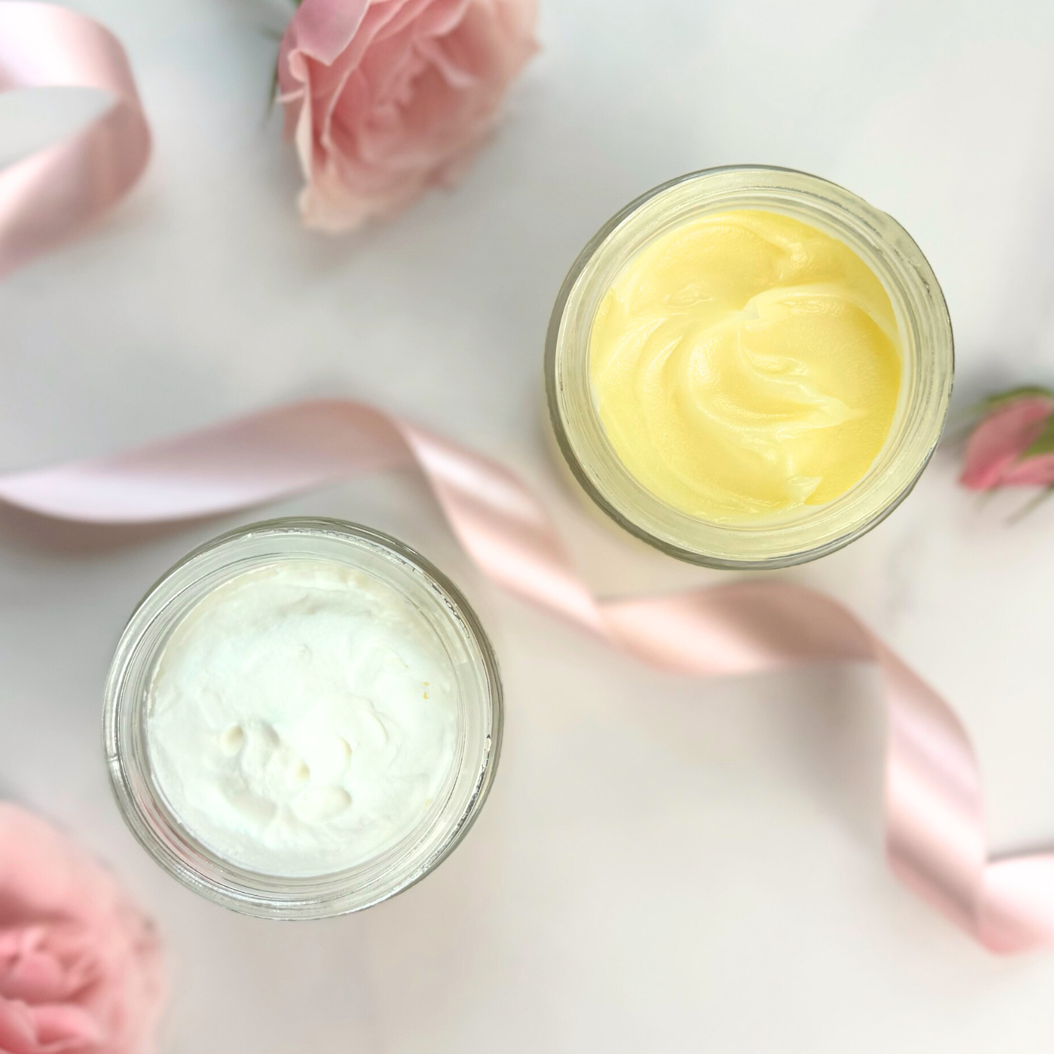 Day & Night Face Moisturizer Duo in jars with pink flowers and ribbon on a marble surface