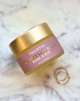 Clara & Fritz Rose Scented Fragrance Balm on marble surface with rings nearby.