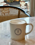 Latte Mug on marble table with Clara & Fritz logo, perfect coffee gift.