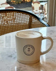 Latte Mug on marble table with Clara & Fritz logo, perfect coffee gift.