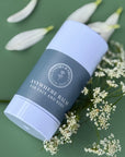 Anywhere Balm for Face and Body by Clara & Fritz on a green background with flowers