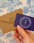 Clara & Fritz Physical Gift Card with kraft envelope in front of a blue patterned background.