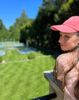 Woman wearing Garment-Washed Logo Hat in garden setting, embracing sunny day.