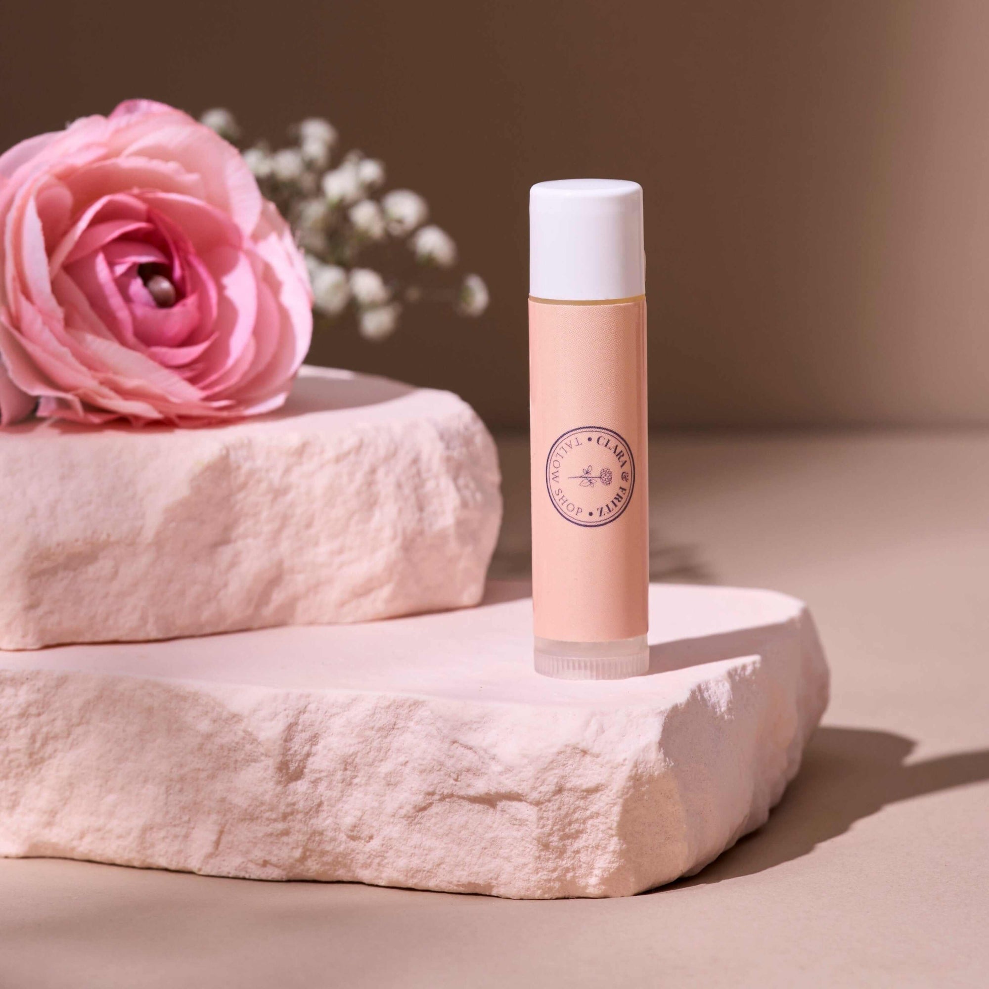 Tallow Lip Balm - Single on a decorative stone with pink floral accent. Also included in Lip Balm Set.