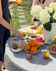 Seaside Garden Block Print Tablecloth used for an alfresco meal setting with fruits and flowers.