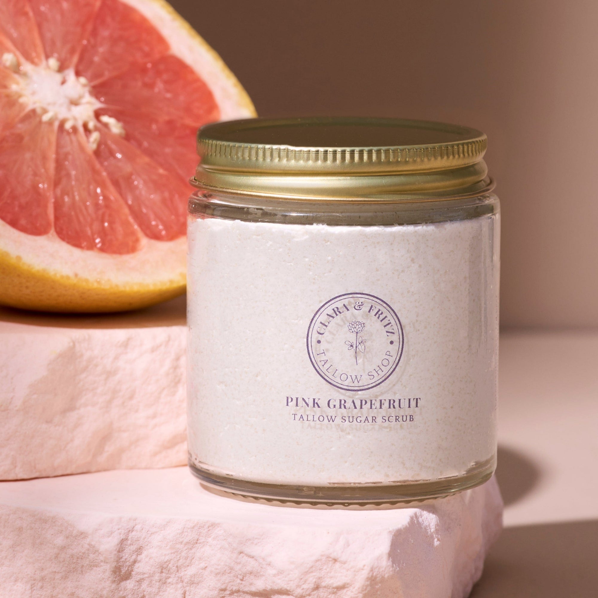 Pink Grapefruit Tallow Sugar Scrub in glass jar with slice of grapefruit, natural exfoliant for soft and refreshed skin.