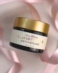 Jar of Timeless Antioxidant Balm with gold lid surrounded by pink ribbon.