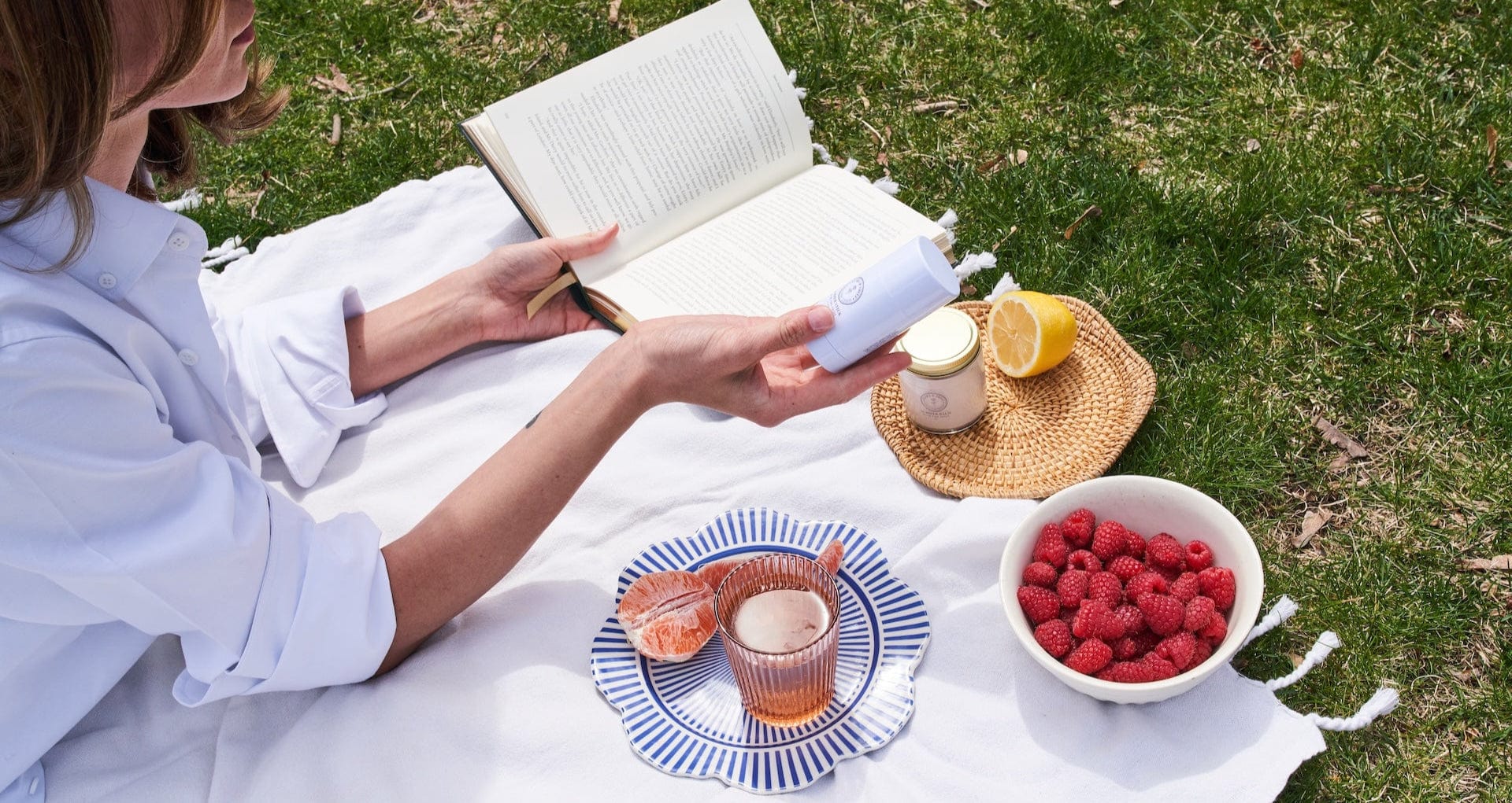 Person reading a book with a picnic setup on grass