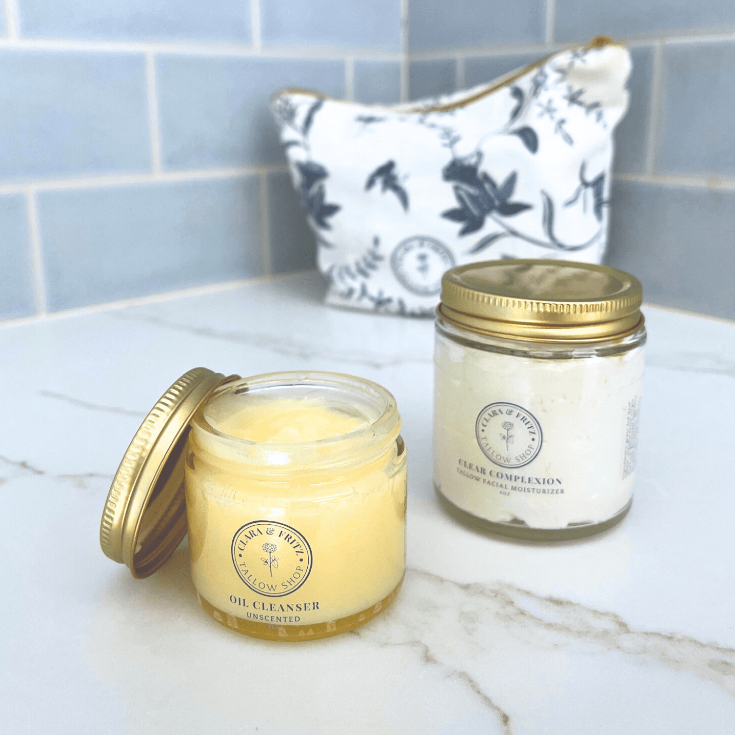 Open jar of Tallow-Based Oil Cleanser with a skincare jar and patterned pouch on a bathroom counter.