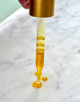 Radiance Instant Glow Facial Serum dropper with golden serum on marble surface, highlighting its hydrating and revitalizing properties.