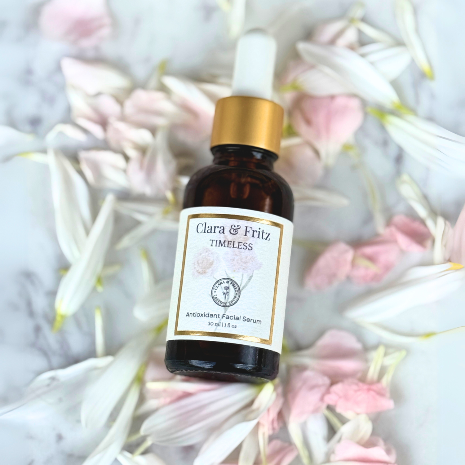 Timeless Antioxidant Facial Serum bottle surrounded by pink and white flower petals on marble surface