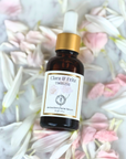 Timeless Antioxidant Facial Serum bottle surrounded by pink and white flower petals on marble surface