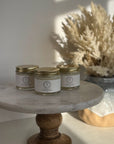 Natural Deodorant in glass jars on a wooden pedestal next to dried floral arrangement