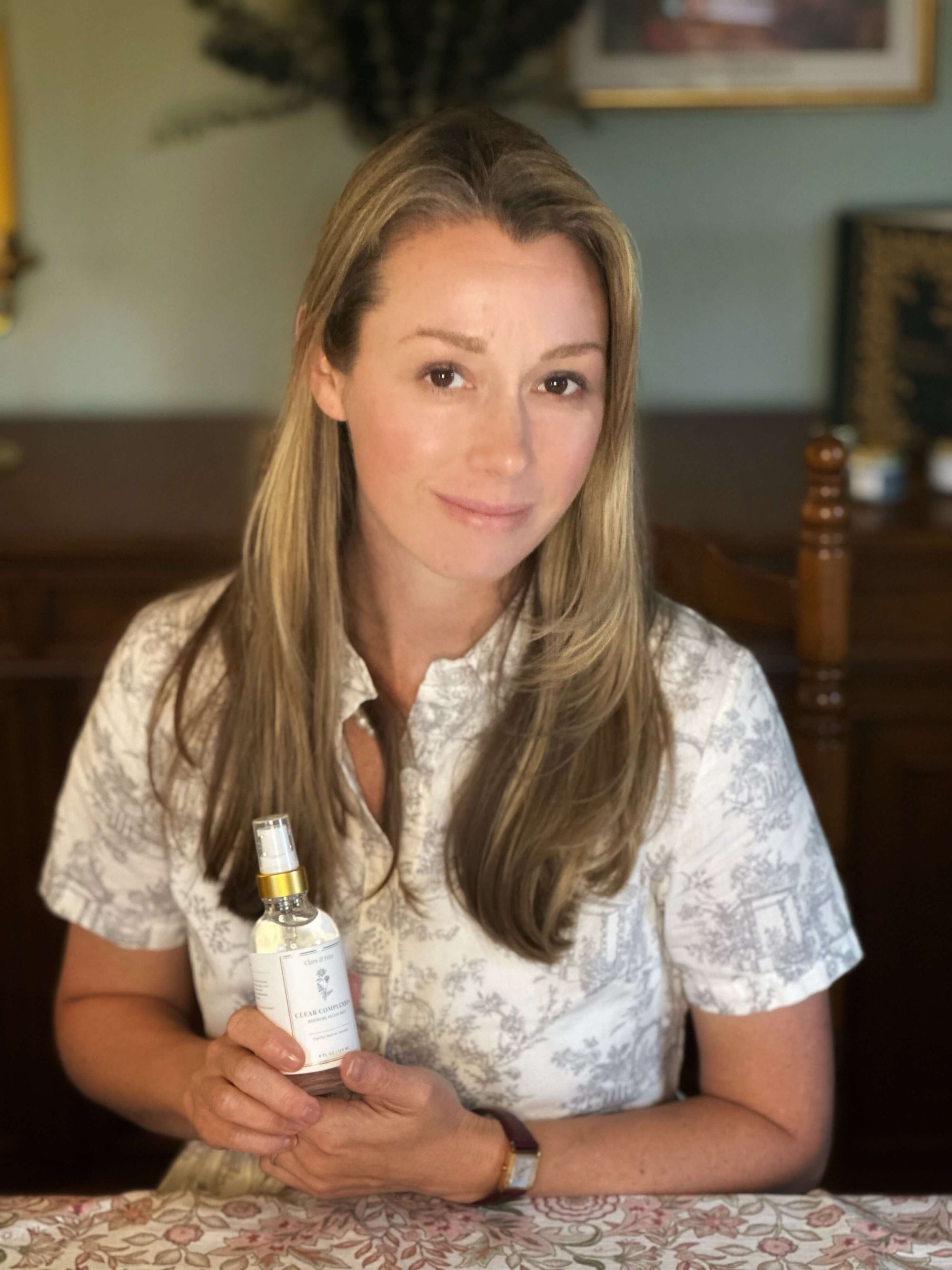 Founder holding Clear Complexion Refining Facial Mist bottle indoors