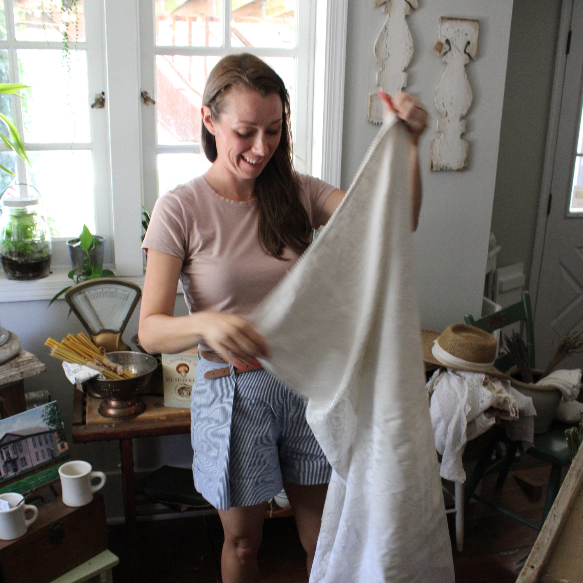 Woman holding a white sheet in a kitchen