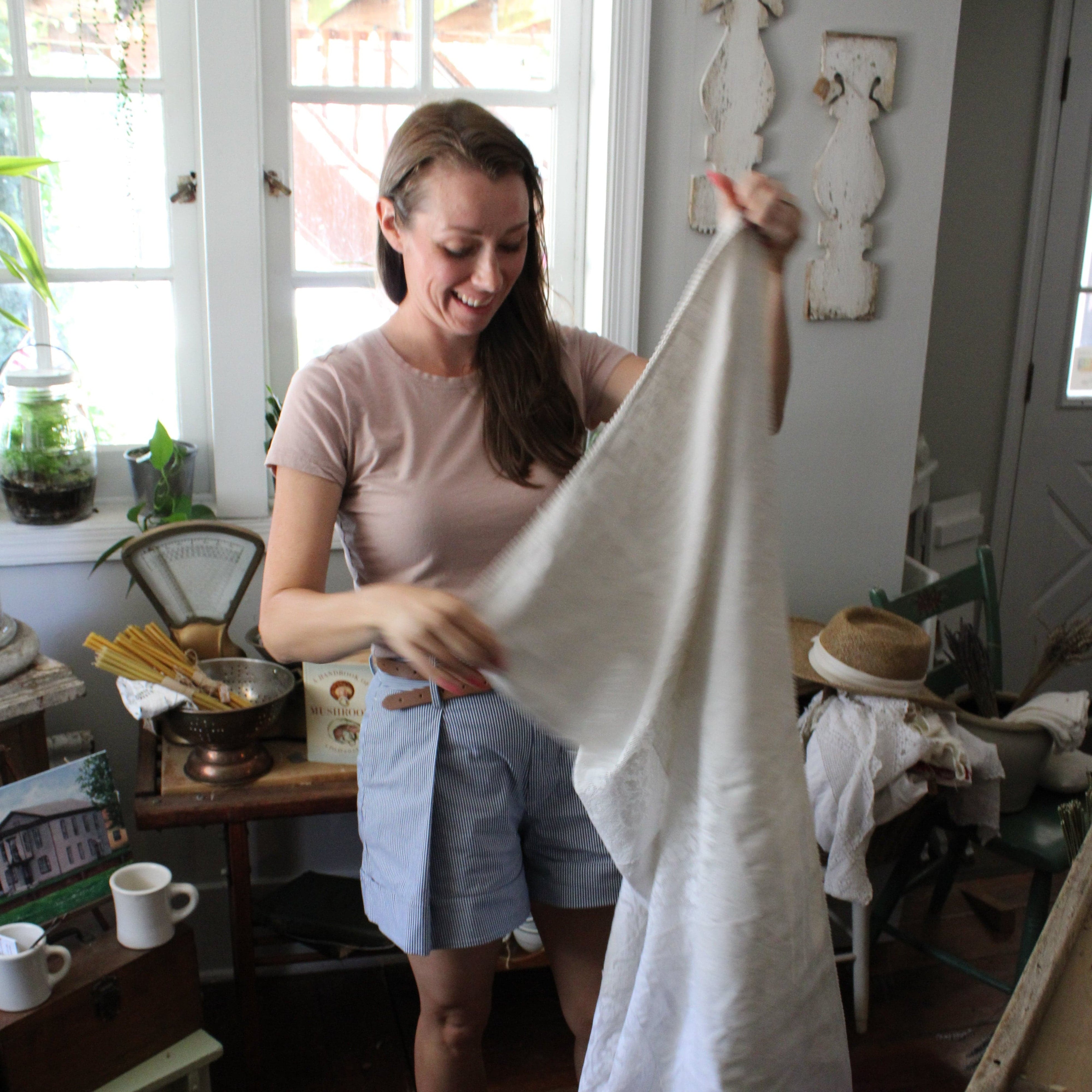 Woman holding a white sheet in a kitchen