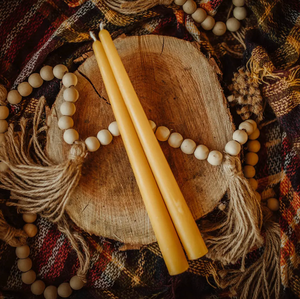 Beeswax Taper Candle on rustic wood surface with decorative beads