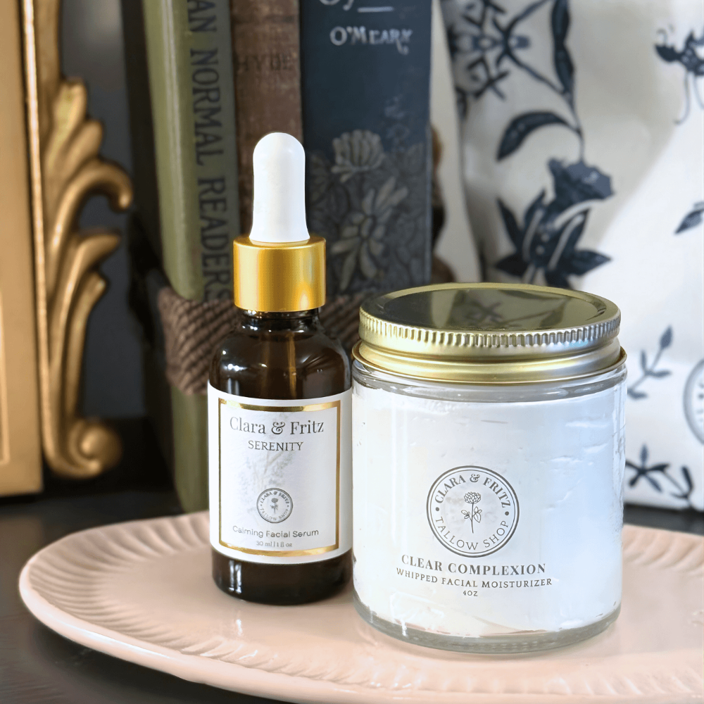 Bottle of Clara & Fritz serum and jar of moisturizer on a plate with books in the background
