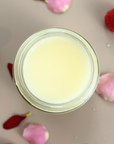 Essential Balm with Infused Calendula in a jar surrounded by petals and raspberries, ideal for natural skincare.