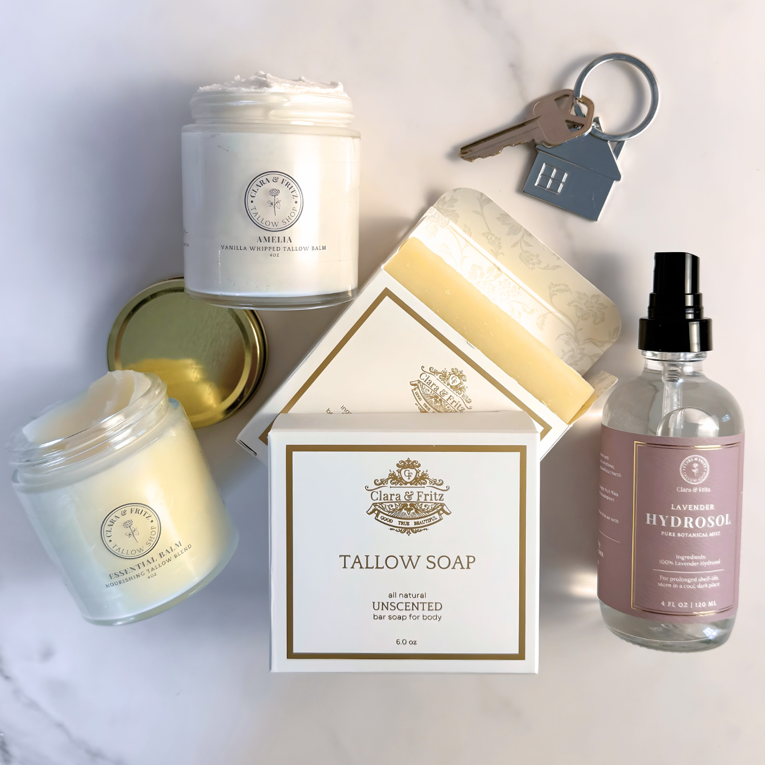 Housewarming Gift Set featuring skincare items, soap, and keychain by Clara & Fritz on a marble surface.