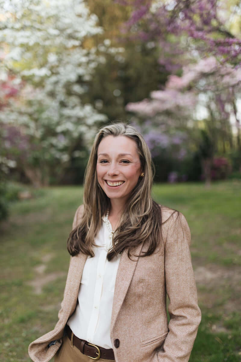 Woman standing outdoors with blooming trees in the background