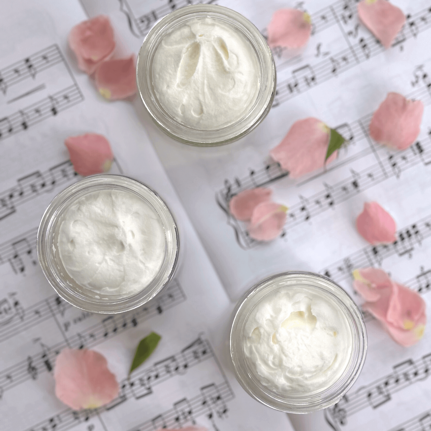 Seasonal Scent Gift Set balm in glass jars on sheet music with rose petals, showcasing its luxurious texture.