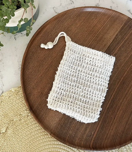 Sisal Soap Saver Pouch on wooden tray, eco-friendly bath accessory for exfoliating and maximizing soap usage.