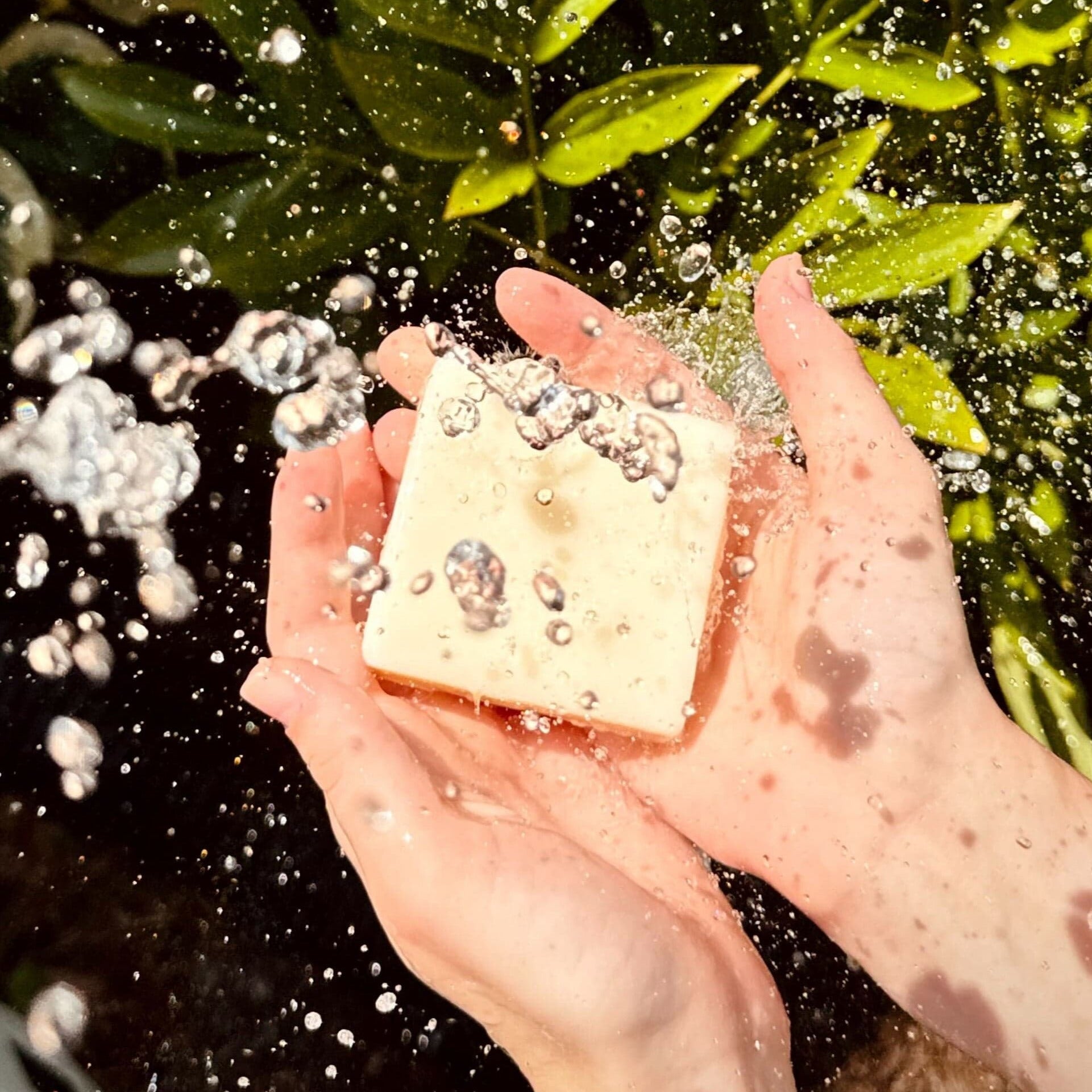hand holding a bar of soap with dripping water